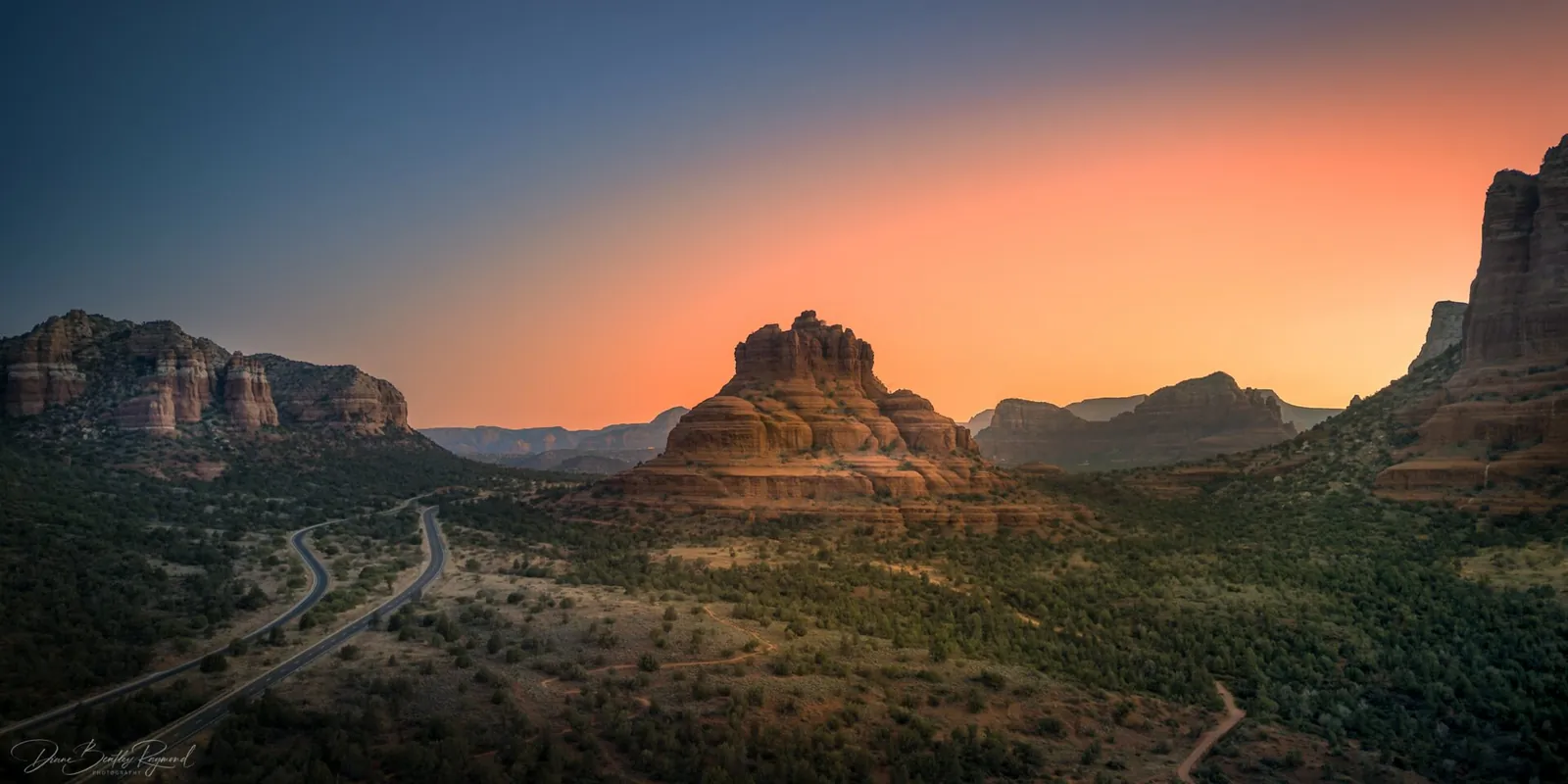 Bell Rock in Sedona glowing against an orange sunset sky