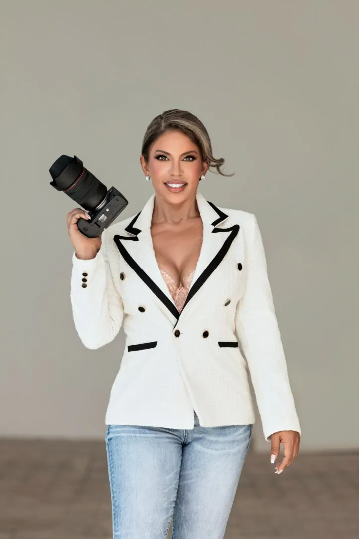 Sarah Lyons Glabman in a white blazer holding her camera